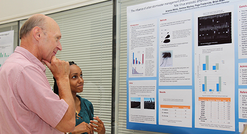 student and faculty member reading scientific poster