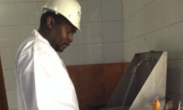 Dr. Takalani Netshituni demonstrates the use of a hands free wash station at a slaughterhouse.