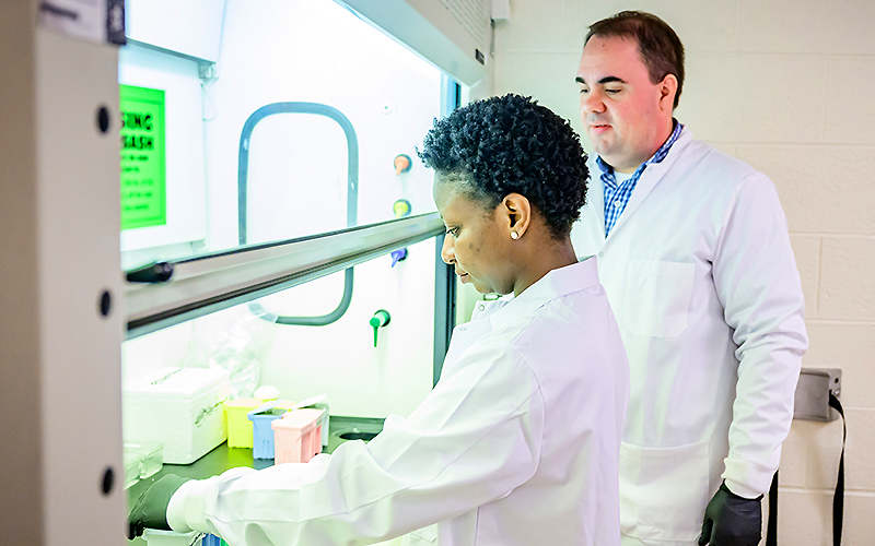 Dr. Gaulke with a lab member working at the hood.