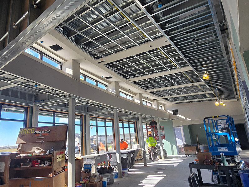 Interior view of the new oncology expansion within the client waiting area at the University of Illinois College of Veterinary Medicine. The space features large windows, exposed ceiling framing for electrical and HVAC systems, and construction equipment as work progresses.