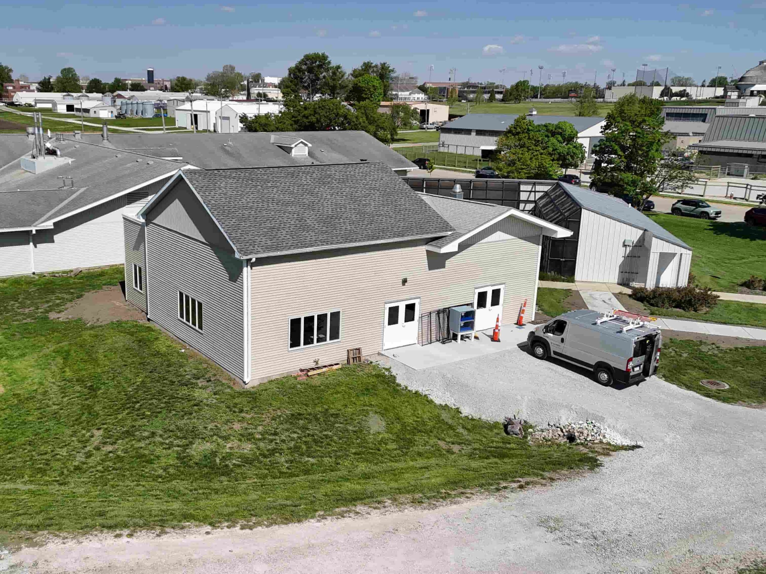 Aerial view of a single-story building with a service van parked outside on a campus setting.