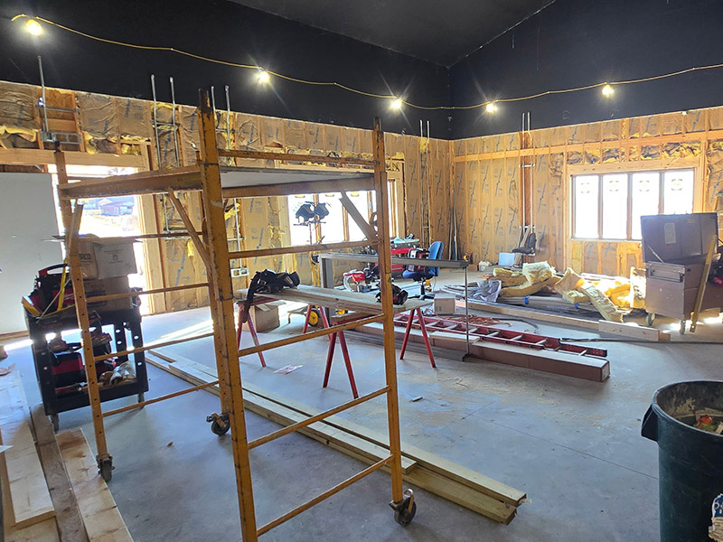 Interior view of the Wildlife Medical Clinic Education Center under construction at the University of Illinois College of Veterinary Medicine. The room features exposed framing, insulation, and newly installed windows, with scaffolding and tools arranged for ongoing work.