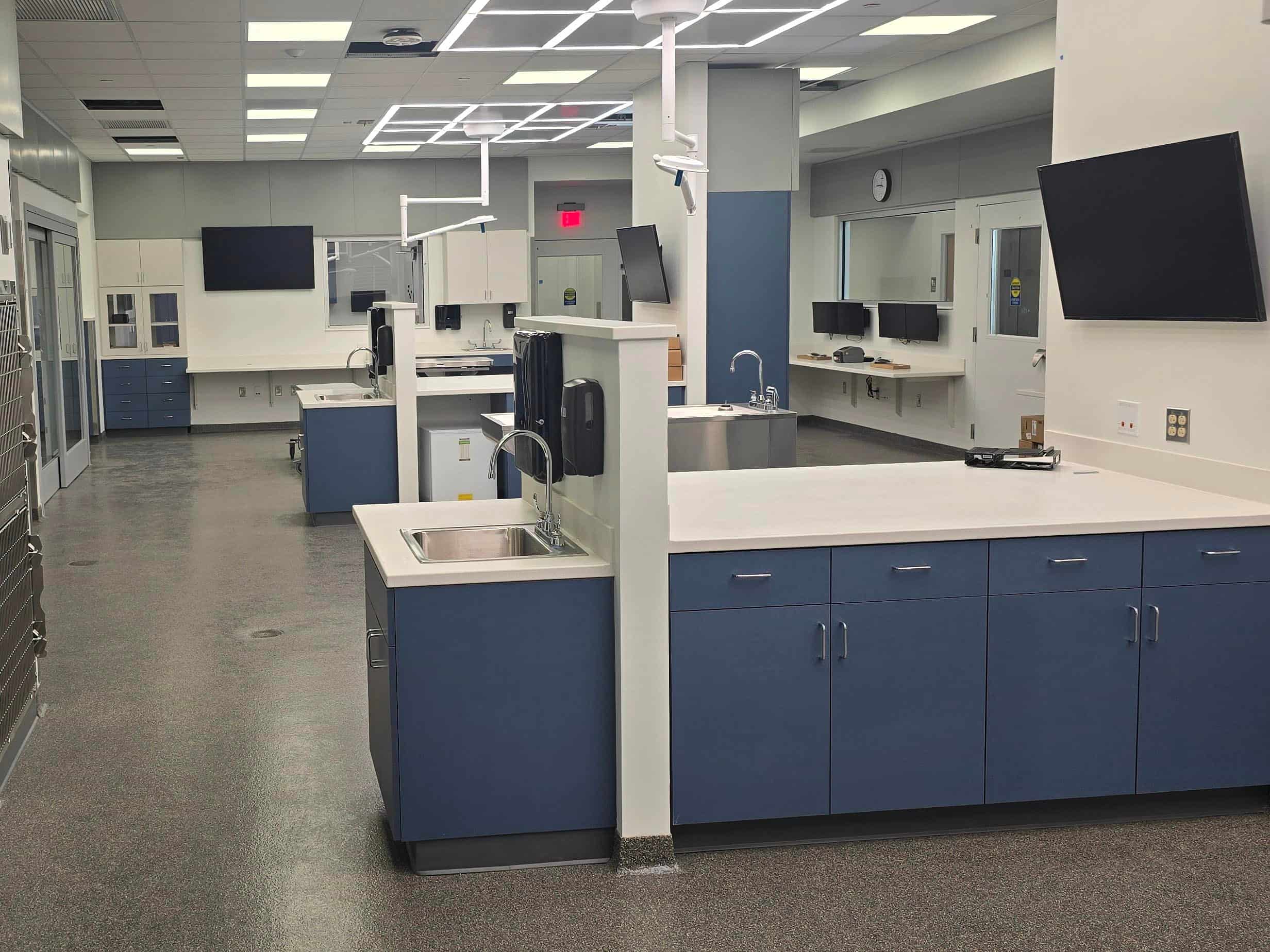 Newly completed oncology treatment room with patient care workstations, sinks, cabinetry, and mounted monitors.
