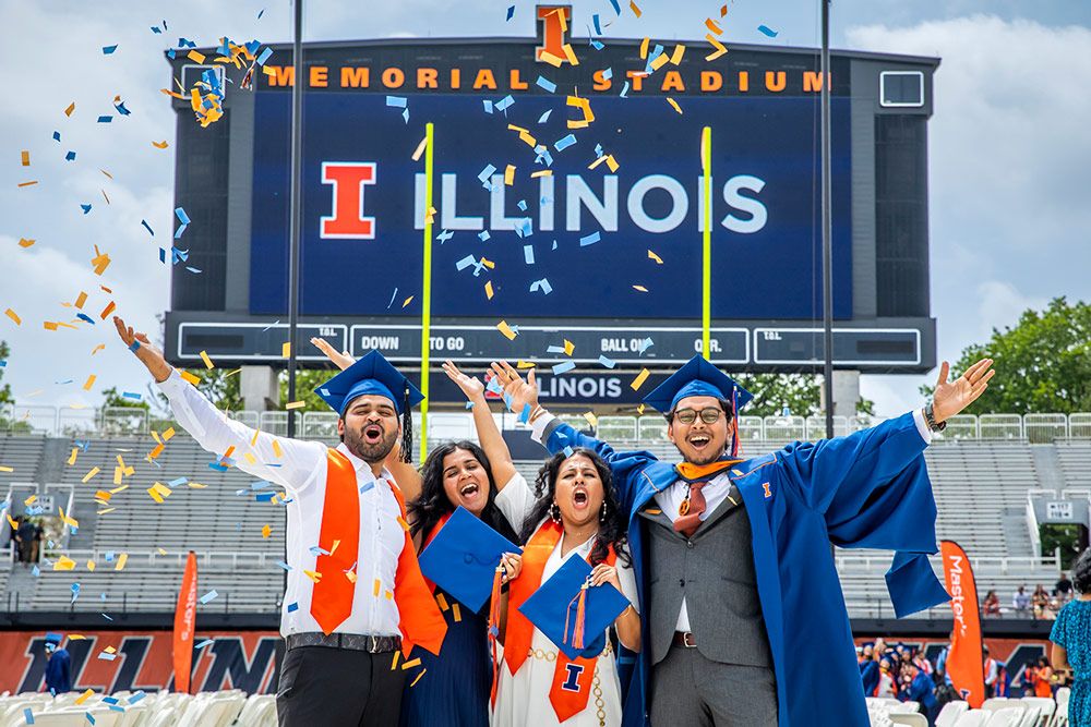 Four Illinois Graduates celebrating their graduation at Memorial Stadium.