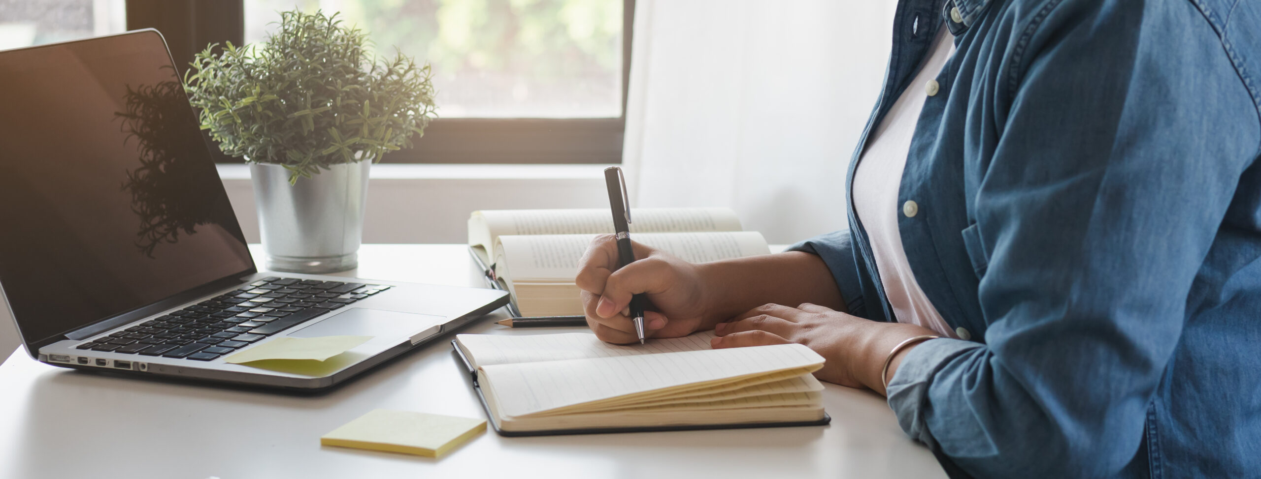 a people write on notebook with laptop upfront