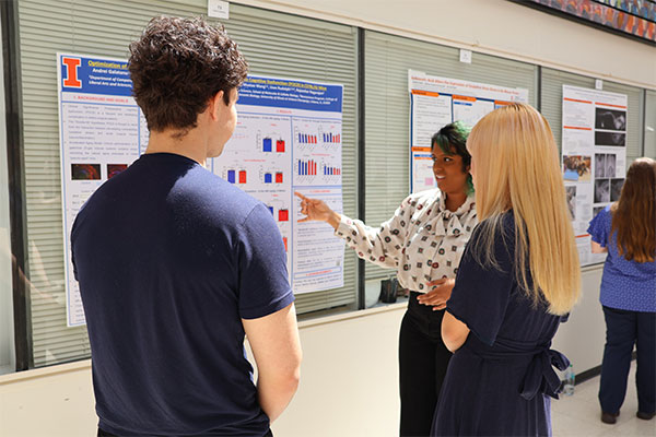 PhD students showing a poster at Research Day