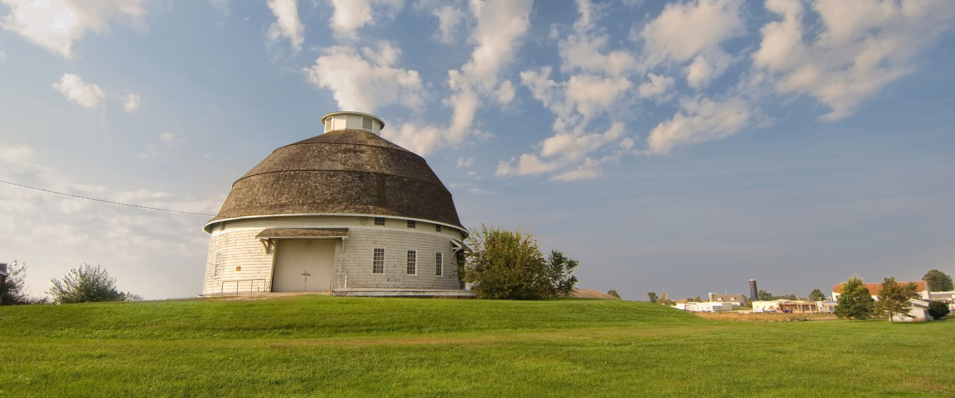 A roundbarn in spring with blue skys ans fluffy clouds