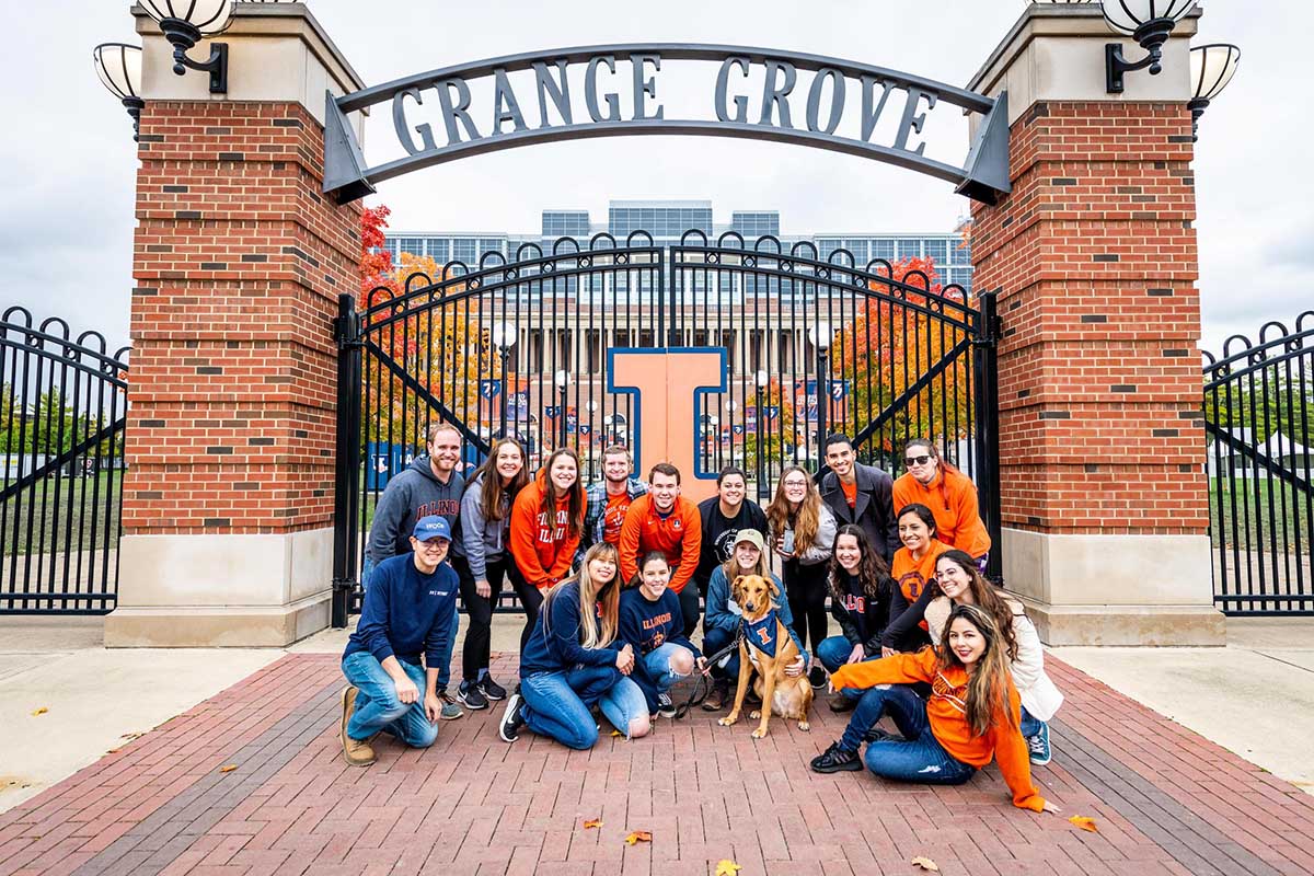 Group of veterinary students and a dog with Block I bandana in front of the gate to Grange Grove 