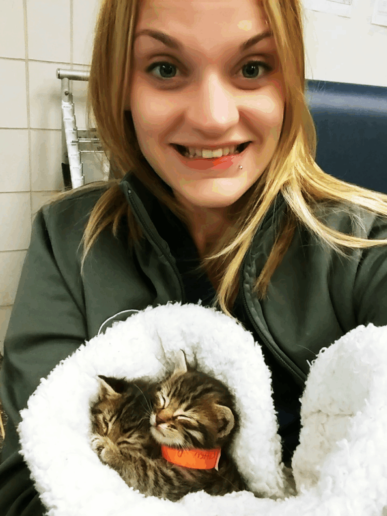 Rachel Dorney holding two kittens wrapped in a blanket.