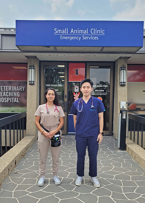Two international veterinary students stand in front of the Small Animal Clinic at the University of Illinois.