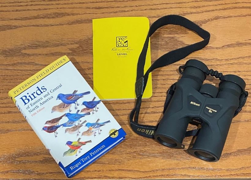 Example of birding equipment - a field guide, binoculars, and a waterproof notebook.