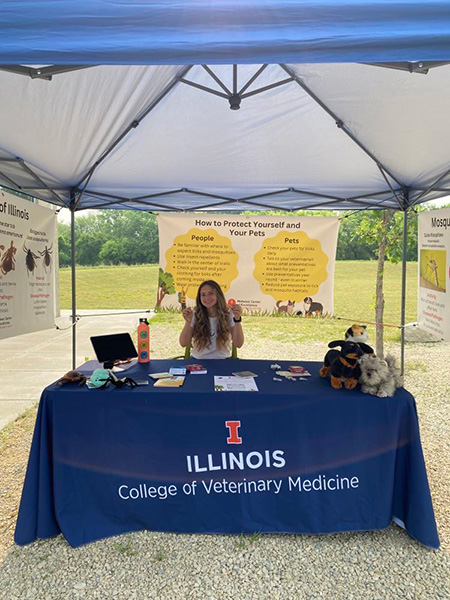 vet student poses in an outdoor info booth about ticks and mosquitoes