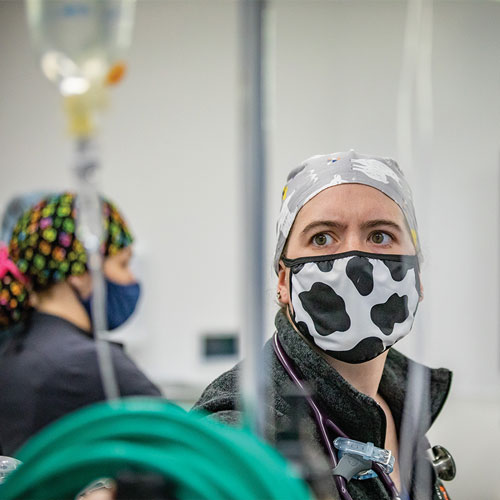 Masked woman looks at a bag of IV fluid