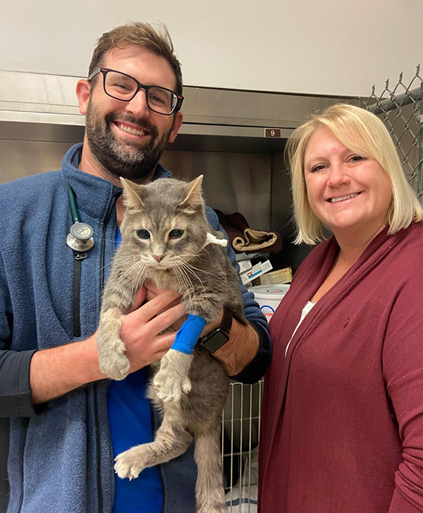 Dr. Jeremy Meyerson holds a cat that is part of a clinical trial to treat oral tumors. Dr. Joanna Schmit stands nearby