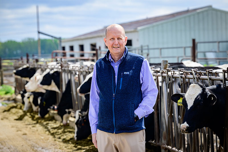 Photo of Dr. Lowe standing in front of a cattle feed lot on the U. of I. campus.