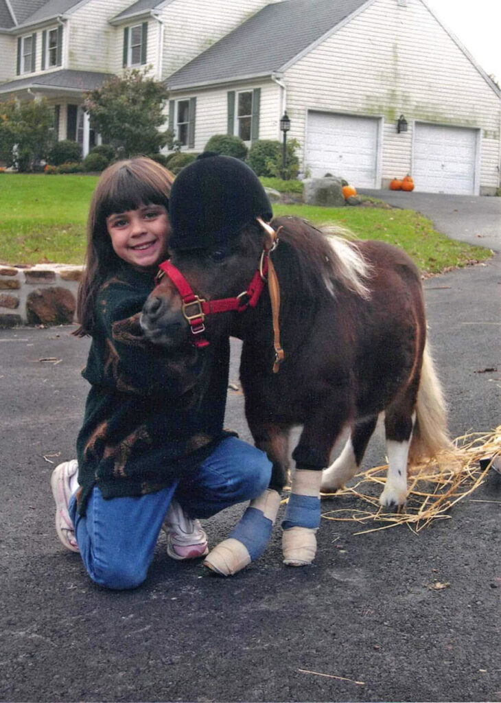 Hannah Streams as a little girl posing next to a baby horse.