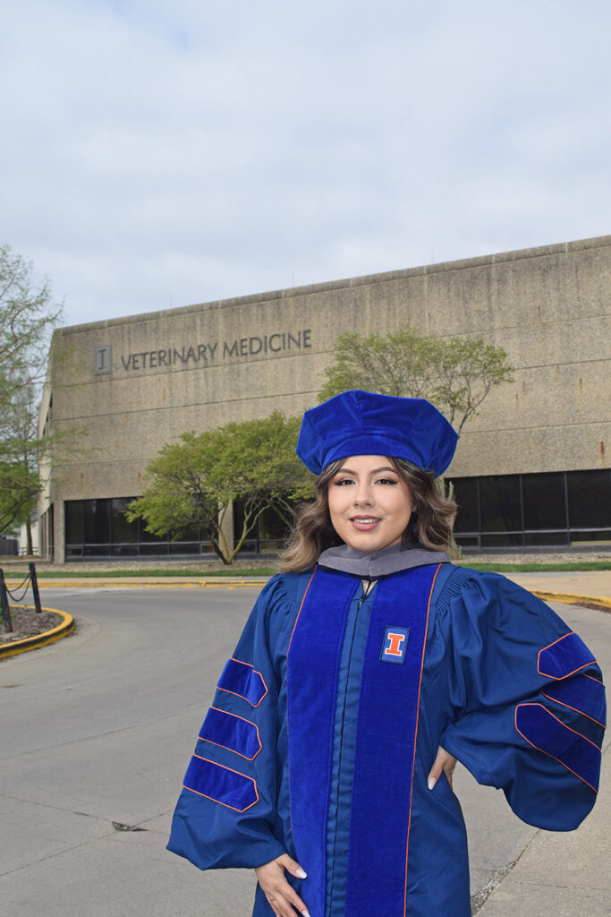 A veterinarian standing in front of the College of Veterinary Medicine at the University of Illinois Urbana-Champaign.