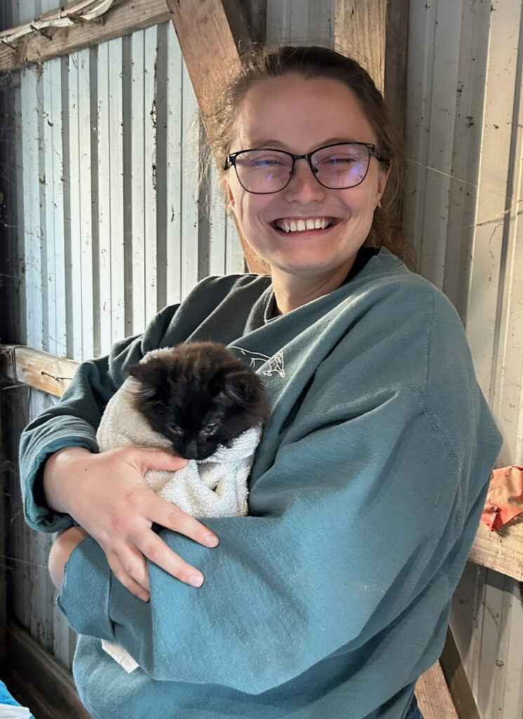 Emily Verwers smiling and holding a barn kitten.