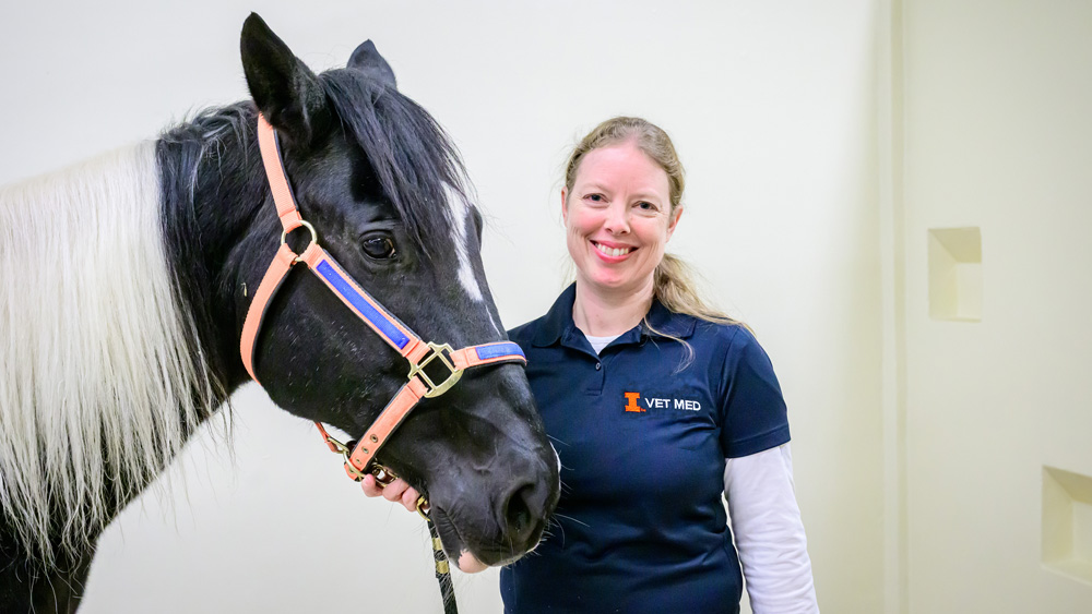 Annette McCoy poses with a horse in the Large Animal Clinic