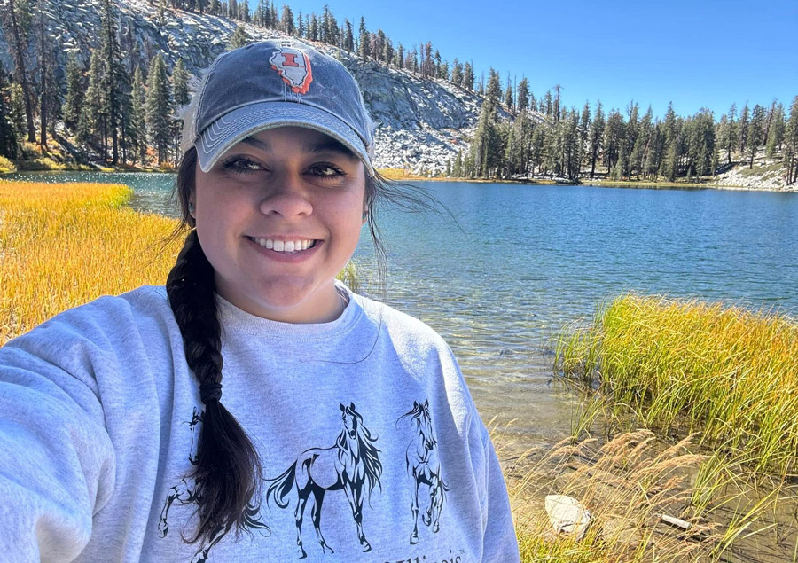 Hannah Streams taking a selfie next to a lake on a sunny day in the mountains.