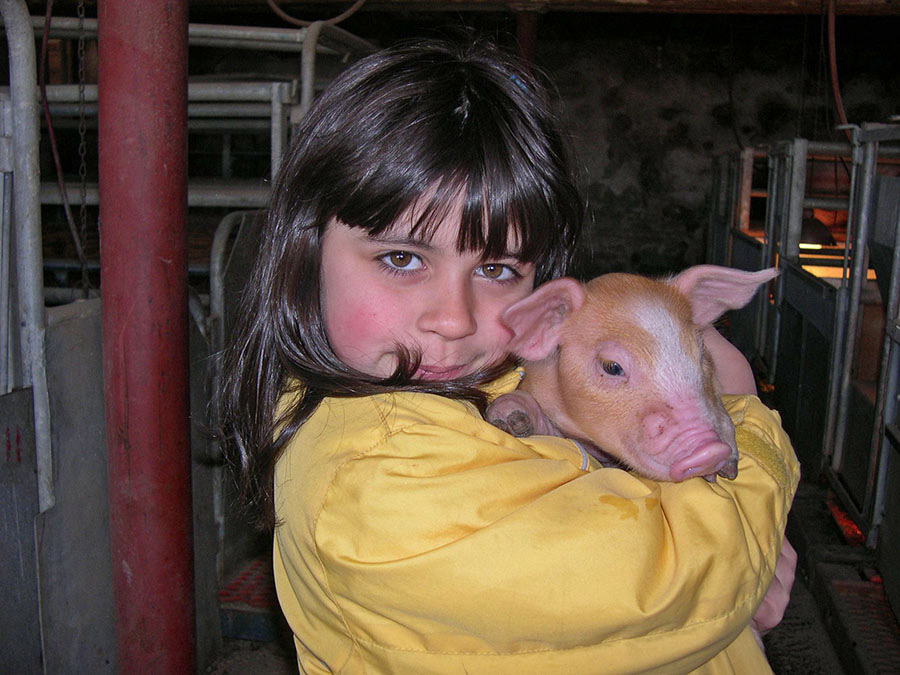Hannah Streams as a little girl holding a piglet.