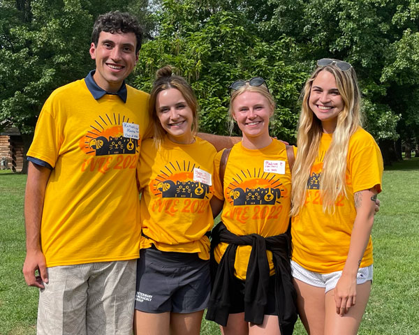 Hassan Hanna posing with three individuals, all wearing Illinois Veterinary Leadership Experience shirts, outside on a sunny day.
