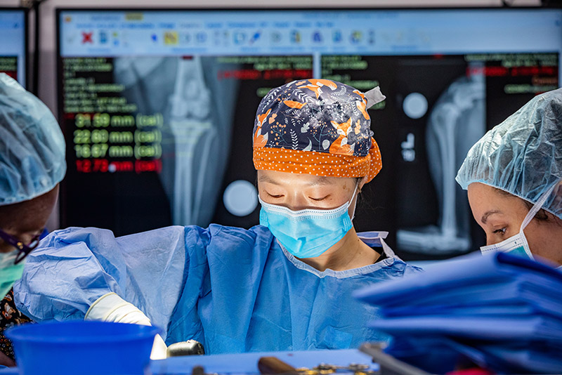 Dr. Chen performing surgery with a digital x-ray blurred in the background