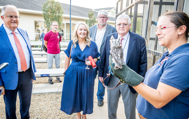 A woman holds an owl on a glove as others watch