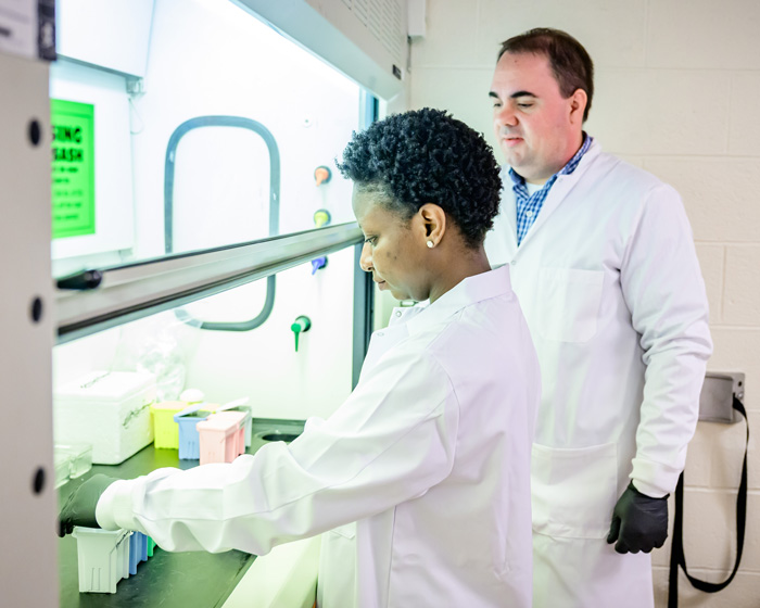 Lydia Okyere and Christopher Gaulke by a fume hood