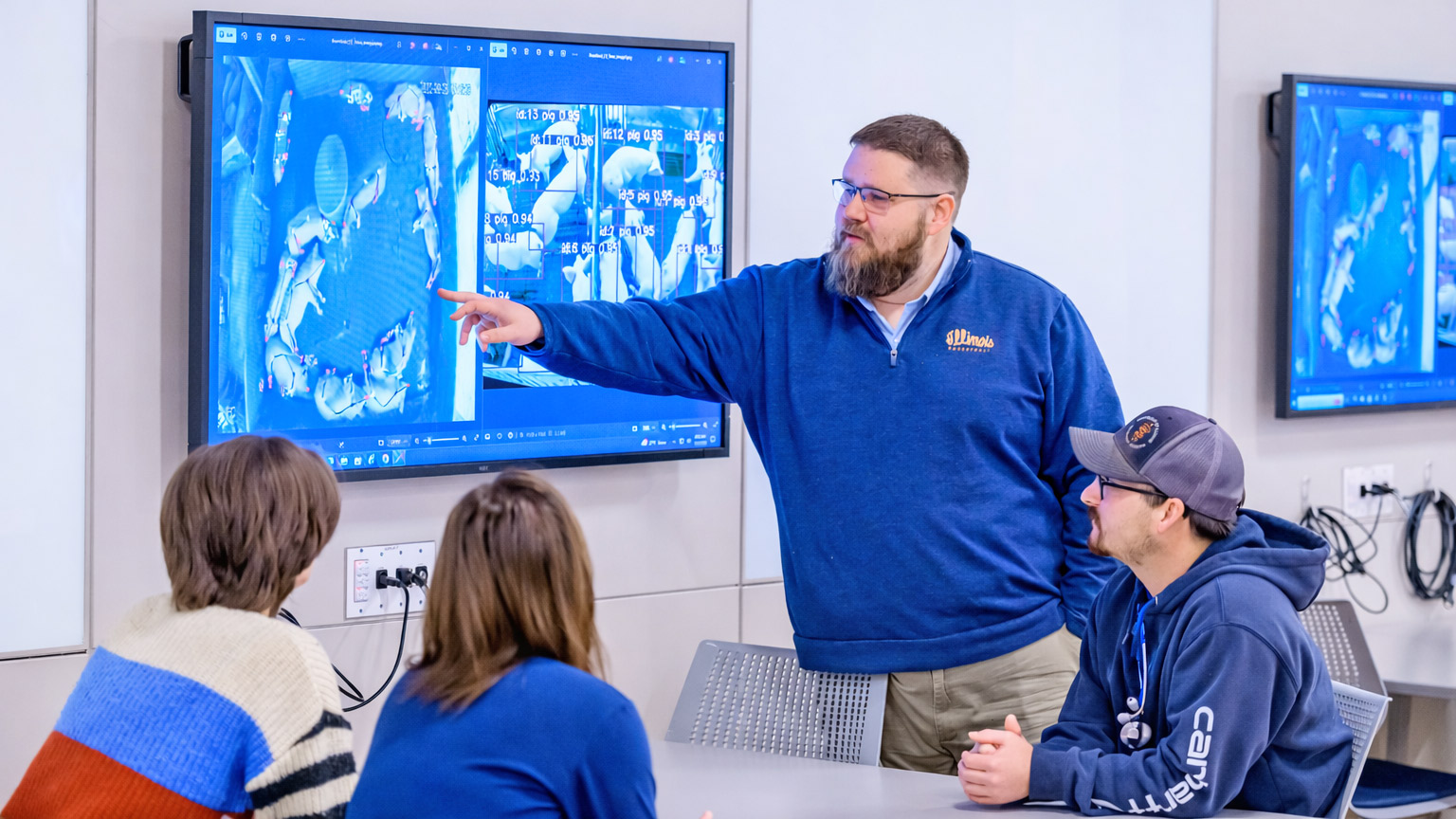 Ben Blair pointing at a TV screen in front of students