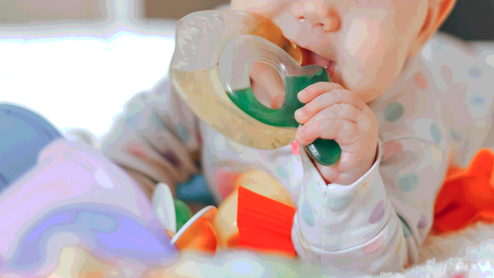 distorted closeup image of baby with plastic teething toy