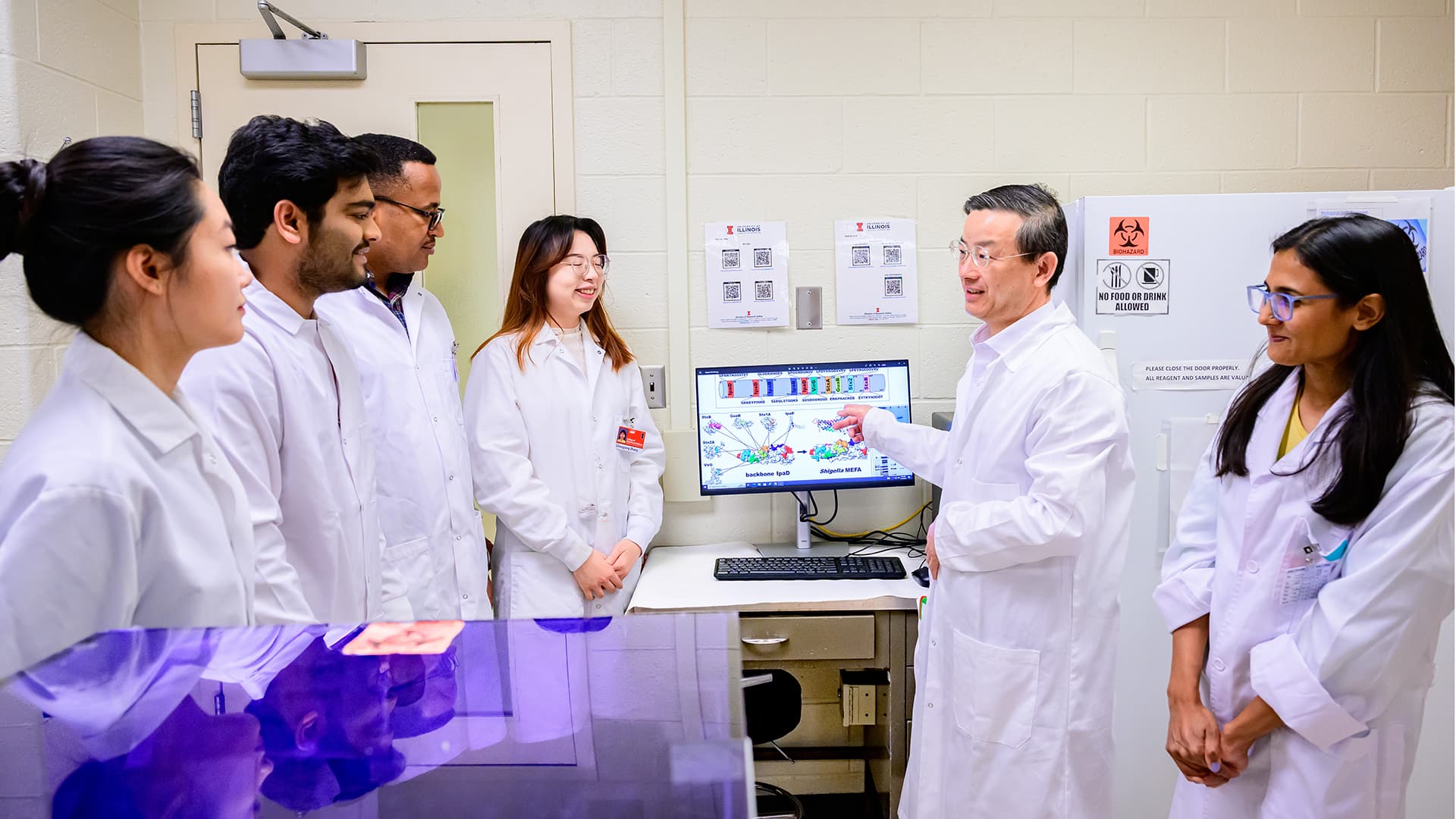 Dr. Zhang and team discussing information on computer screen.